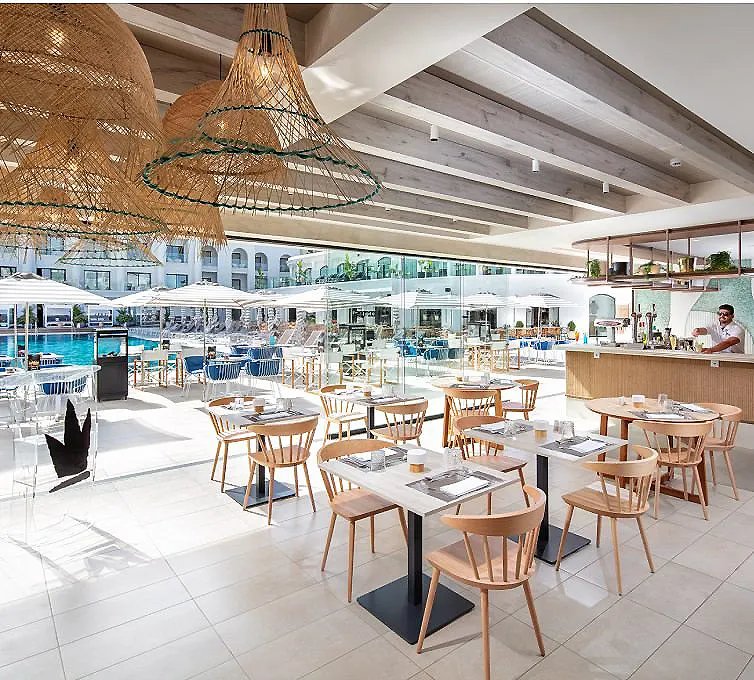 Restaurante con mesas de madera y sillas, zona exterior junto a piscina