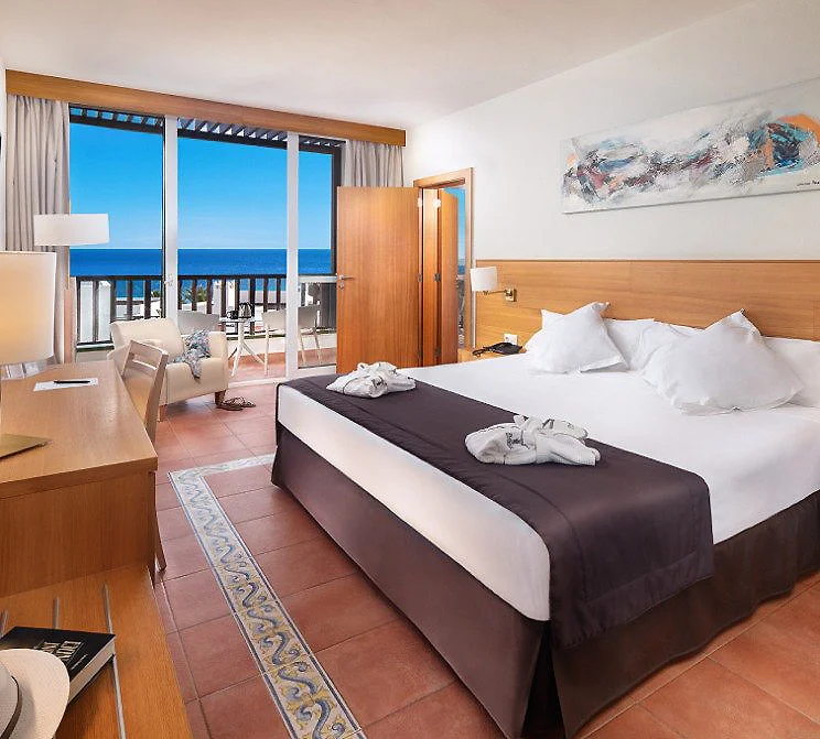 Habitaci&oacute;n de hotel con cama doble y balc&oacute;n frente al mar.