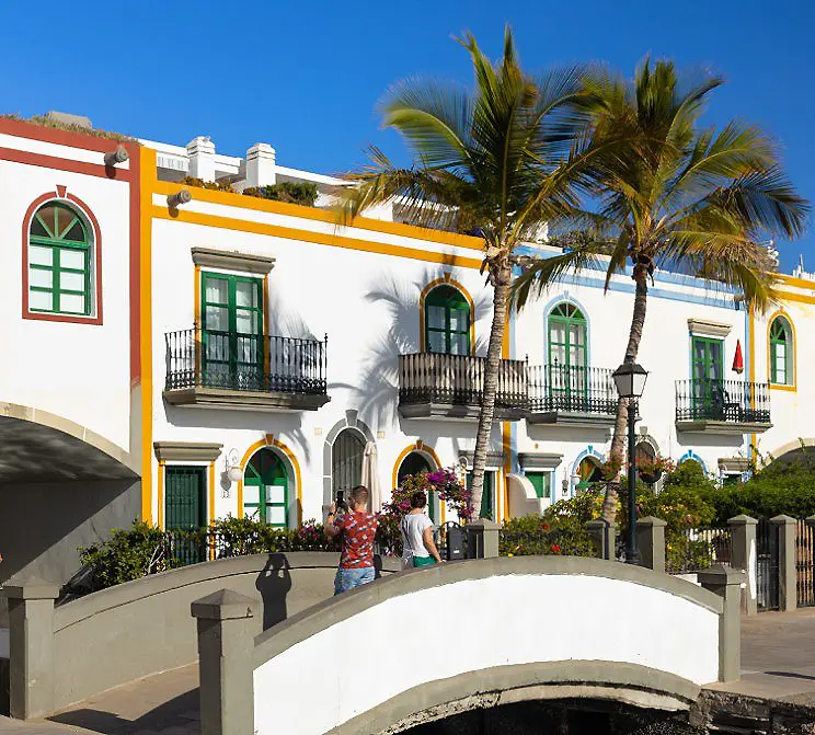 Patio andaluz con palmeras y casas blancas con ventanas verdes al sol