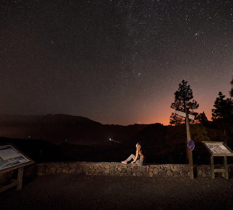 Persona sentada en una terraza al atardecer, bajo un cielo estrellado