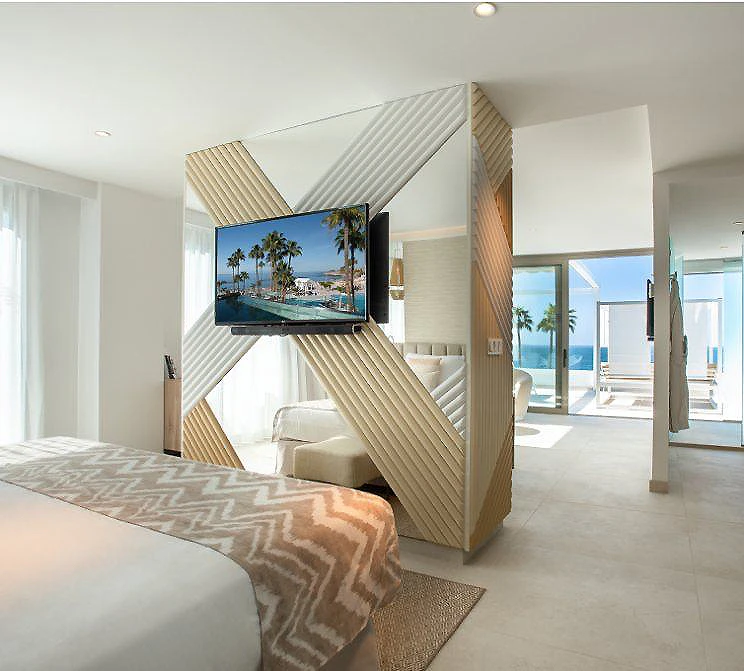 Habitaci&oacute;n moderna con pantalla de TV y vista al mar desde el sal&oacute;n.