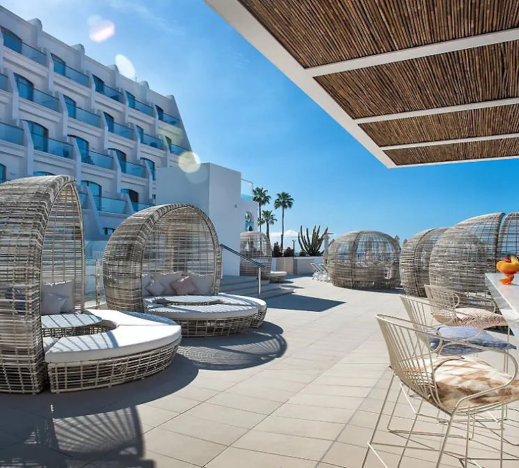 Terraza con camas y c&uacute;pulas de malla transparente en resort, cielo azul