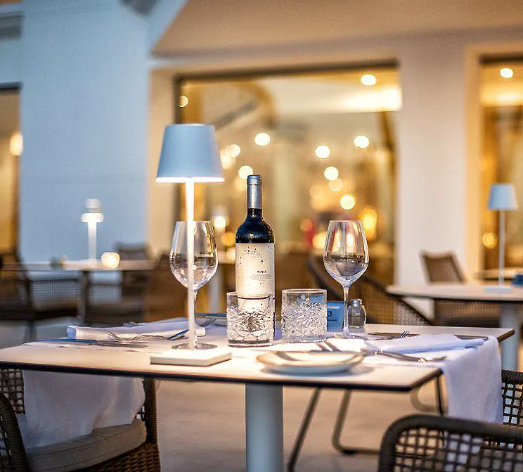 Mesa de restaurante con botellas de vino y copas bajo luces c&aacute;lidas
