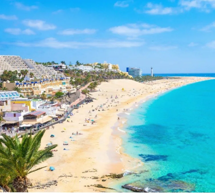 Playa de arena clara con palmeras y hoteles junto al mar turquesa