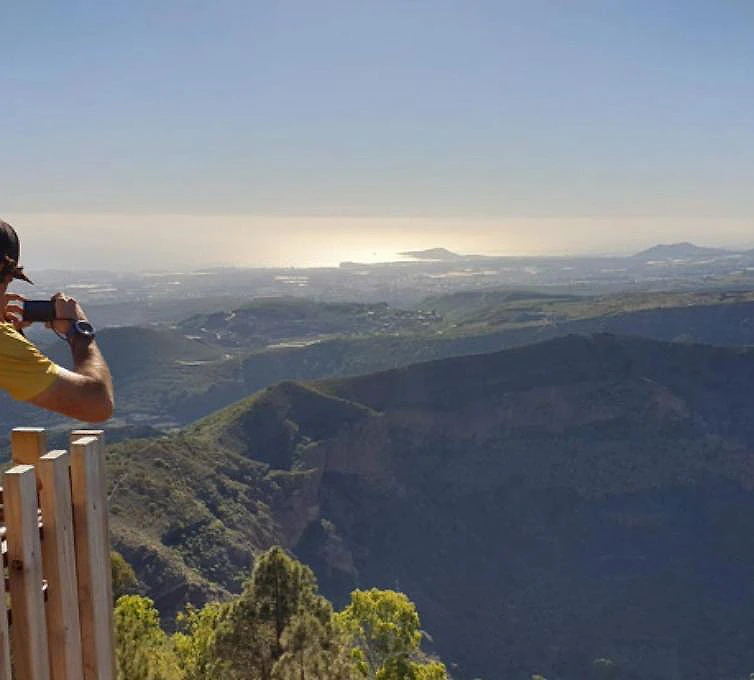 Persona con chaleco mirando un paisaje monta&ntilde;oso al atardecer.