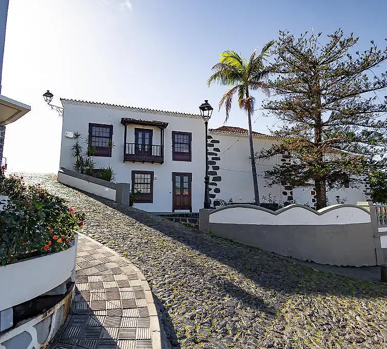 Casa blanca con puertas y ventanas negras, camino de piedra y jard&iacute;n
