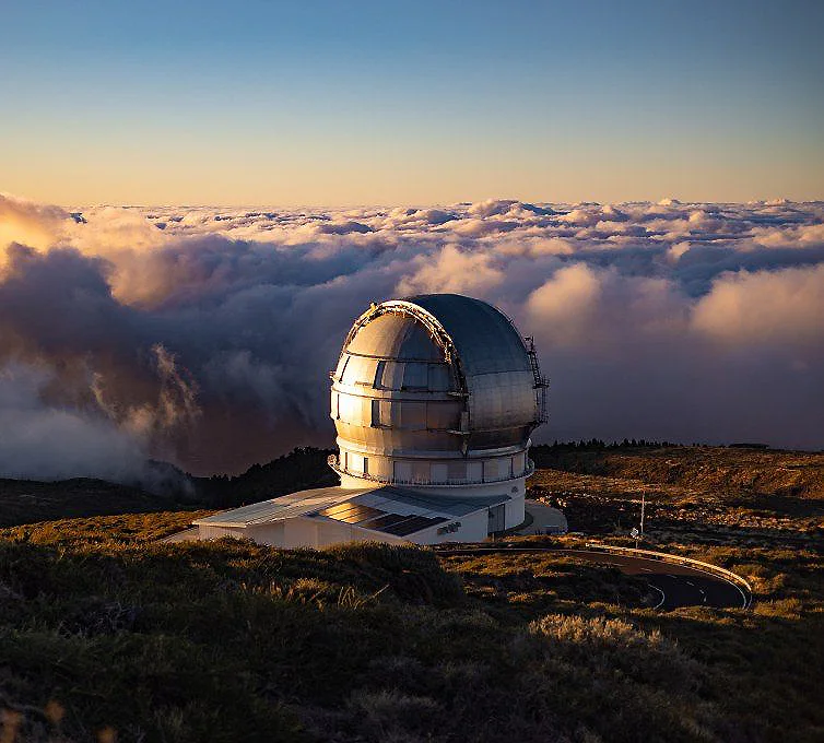 Observatorio astron&oacute;mico sobre nubes al atardecer en la cima de una monta&ntilde;a