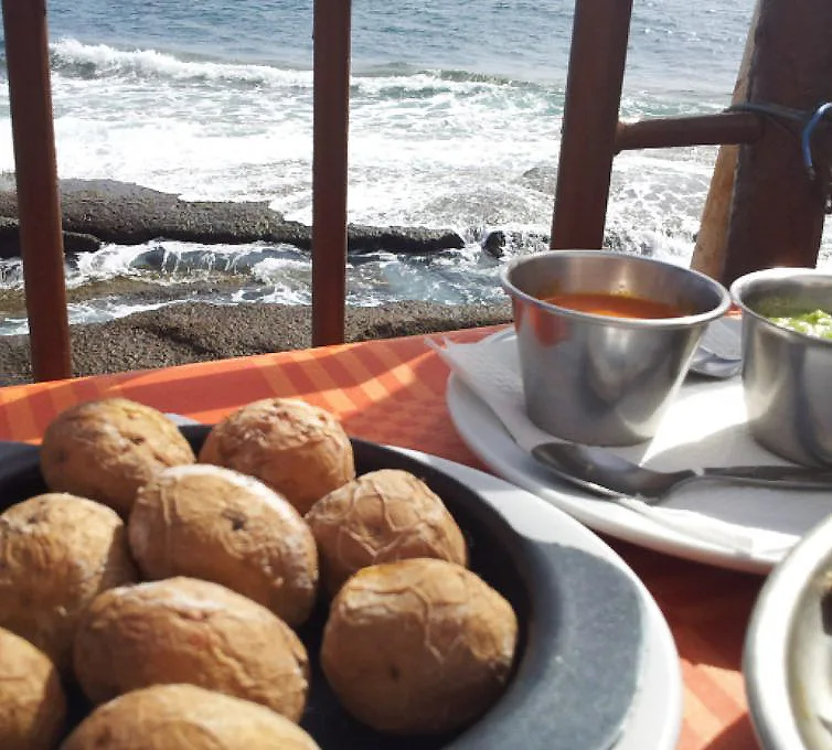 Mesa con pan y taza de caf&eacute; frente al mar con olas desde un barco