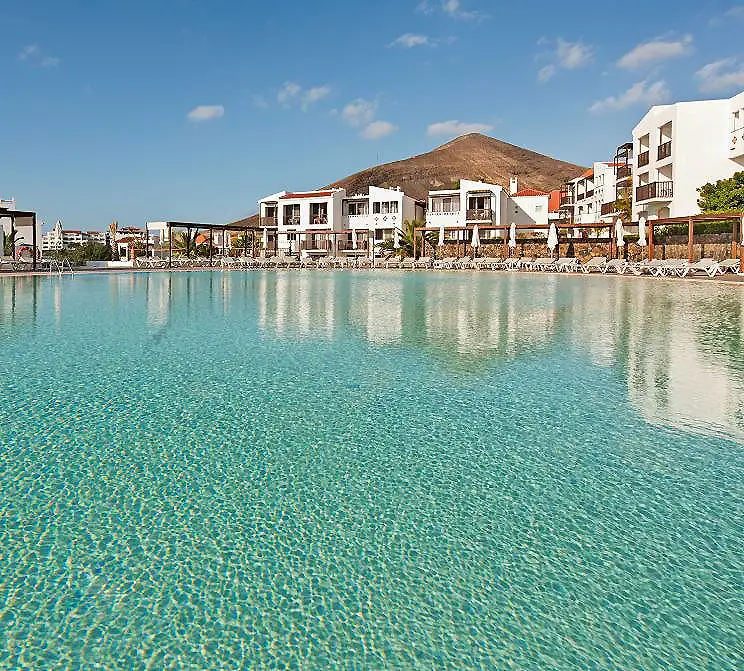Piscina con edificios blancos frente a una monta&ntilde;a bajo cielo despejado