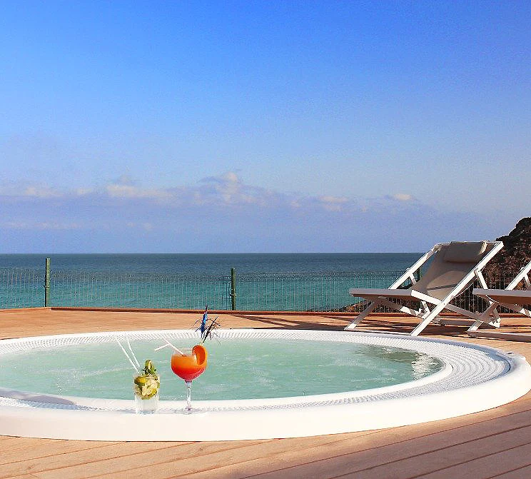 Piscina con tumbonas junto al mar, cielo azul y vista panor&aacute;mica