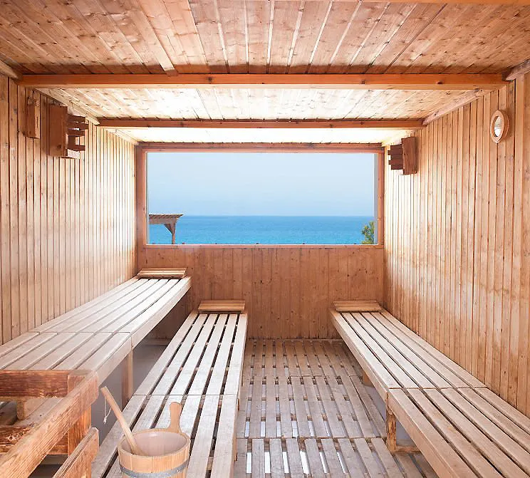 Interior de sauna de madera con bancos y vista al mar por la ventana.