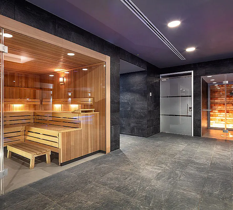 Sauna de madera y espacio de spa moderno con baldosas grises e iluminaci&oacute;n LED