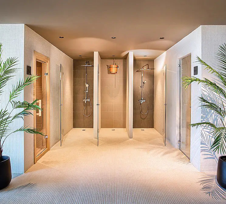 Pasillo con dos duchas y plantas en macetas, dise&ntilde;o moderno de ba&ntilde;o.