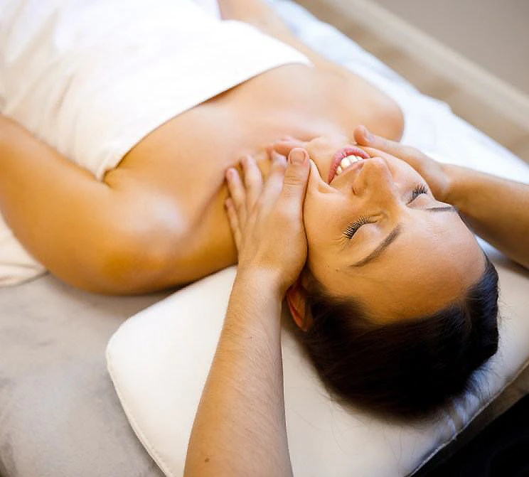 Mujer recostada con los brazos sosteniendo el rostro, relajada.