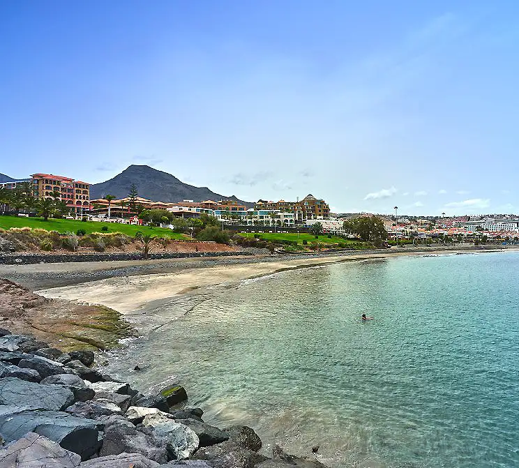 Playa con acantilados y hoteles junto a la costa, cielo azul y monta&ntilde;as