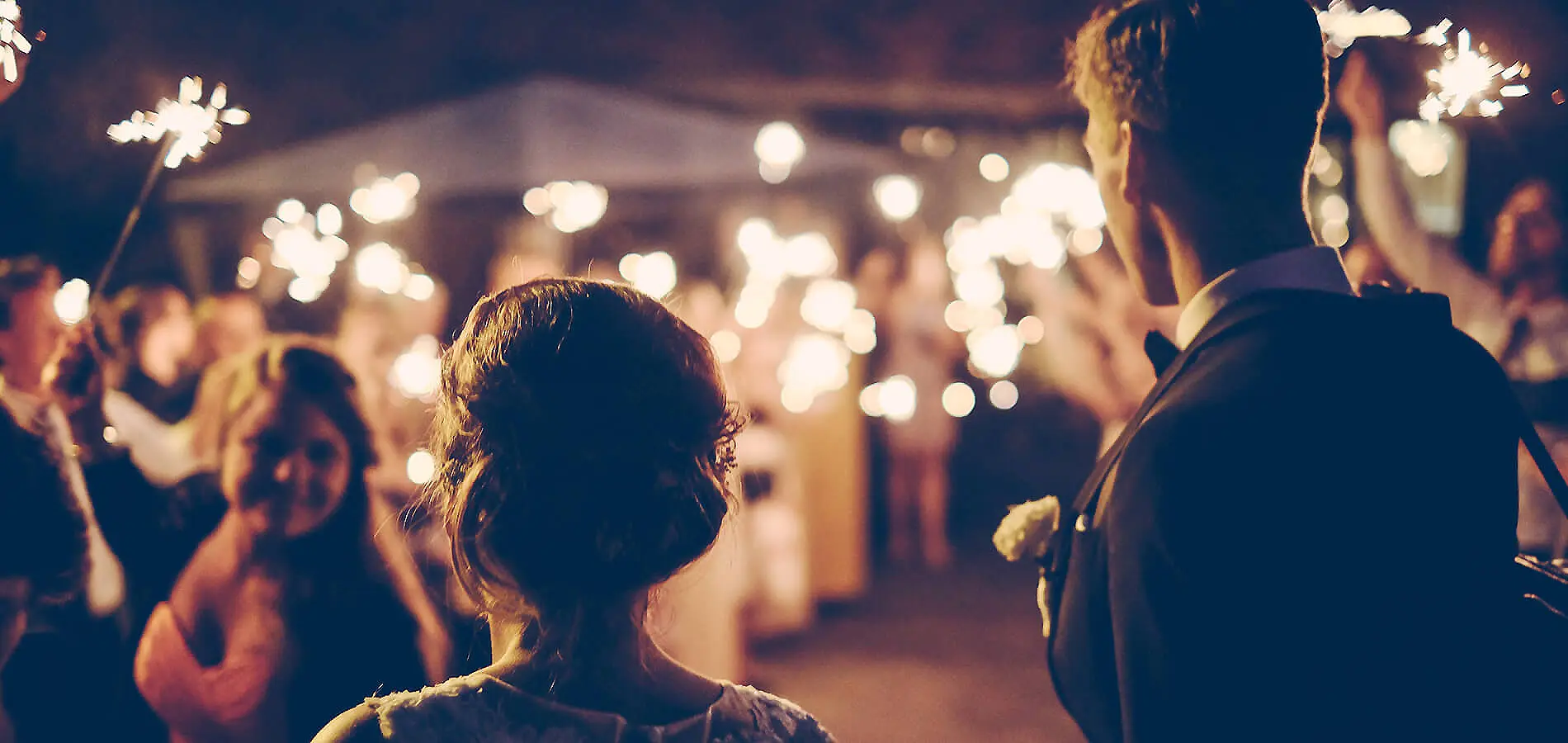 Dos personas en concierto con luces y escenario desenfocado al fondo