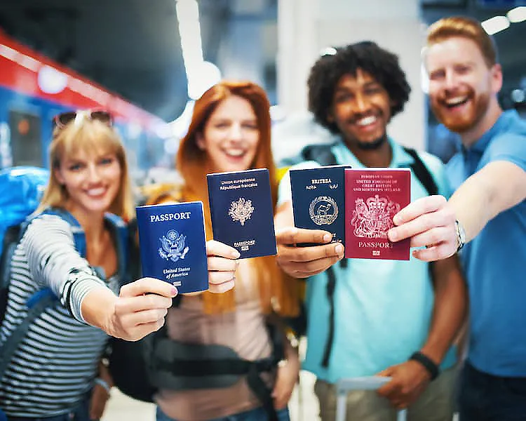 Grupo de personas sonrientes mostrando pasaportes y documentos de viaje.