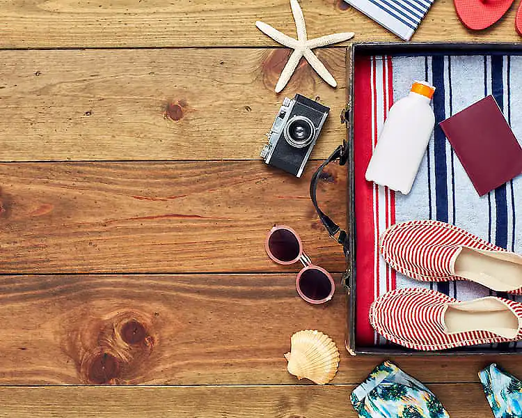 Vista superior de accesorios de playa: toalla, gafas, c&aacute;mara y conchas.
