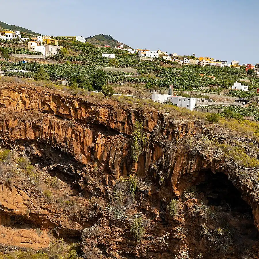 Acantilado rocoso con cuevas y casas blancas en la ladera, paisaje costero