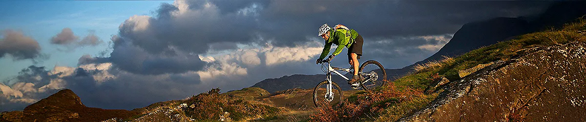 Ciclista en bicicleta de monta&ntilde;a con casco verde en una ladera rocallosa.