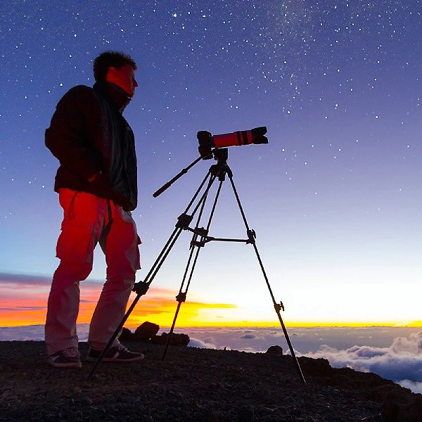 Astr&oacute;nomo con tr&iacute;pode y telescopio ante un cielo estrellado al atardecer