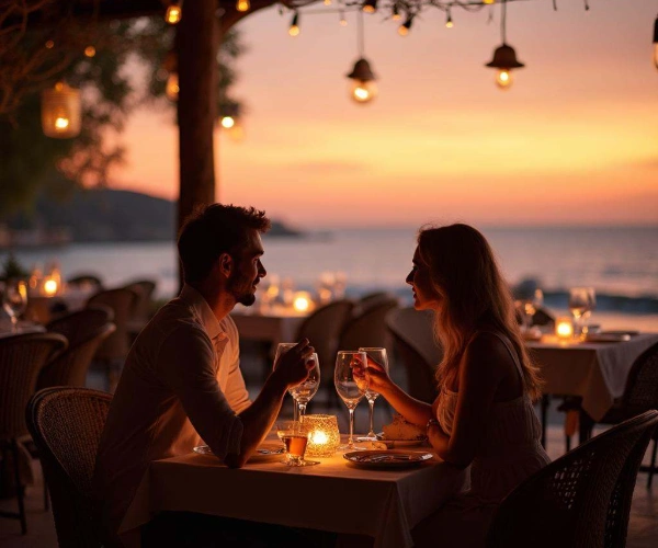 Pareja cenando al atardecer en la playa, con velas y luces colgantes