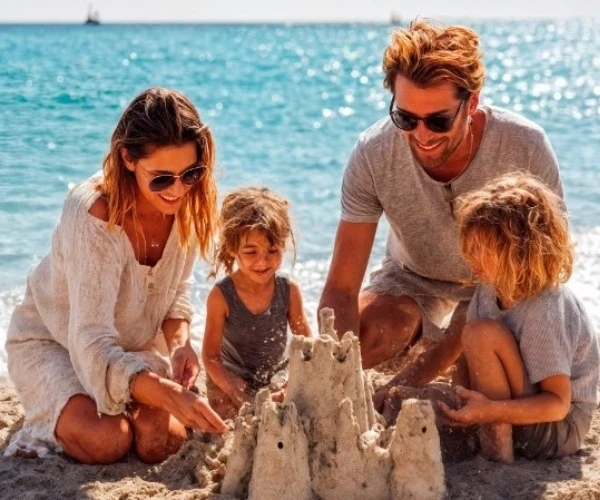 Familia en la playa construyendo un castillo de arena con palas