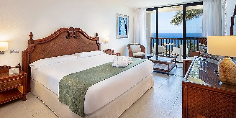 Habitaci&oacute;n de hotel con cama doble, balc&oacute;n y vista al mar.