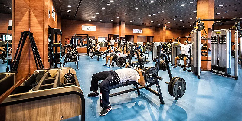 Gimnasio con m&aacute;quinas y una persona haciendo press en banco.