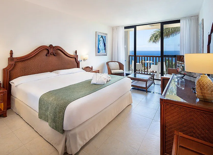 Habitaci&oacute;n de hotel con cama doble y balc&oacute;n con vista al mar.
