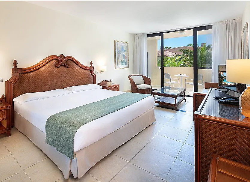 Dormitorio con cama doble y salida a balc&oacute;n con vistas tropicales