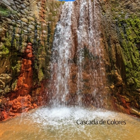 Cascada de agua entre rocas; al fondo una cortina de agua blanca y verde.