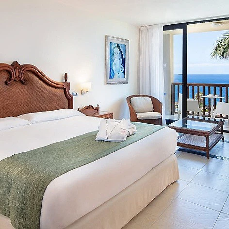 Dormitorio con cama doble y balc&oacute;n con vista al mar.