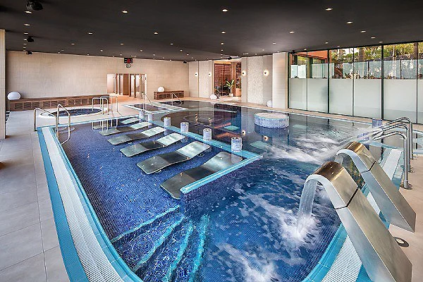 Piscina interior con chorros y tumbonas en un spa moderno