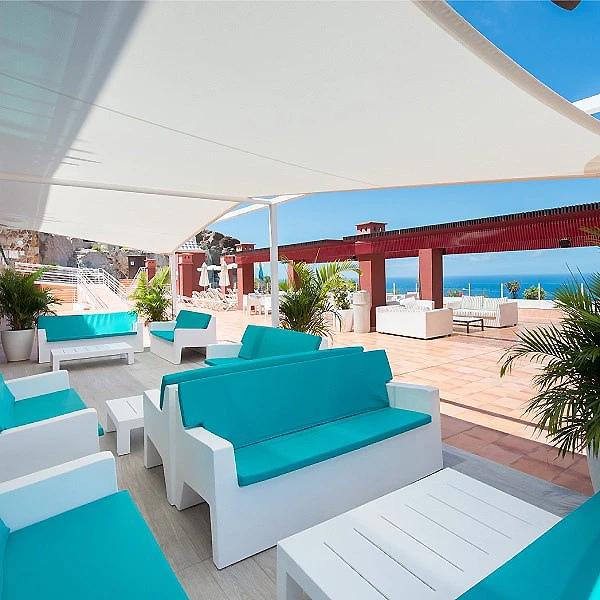 Terraza con sof&aacute;s azules y vista al mar bajo una carpa blanca