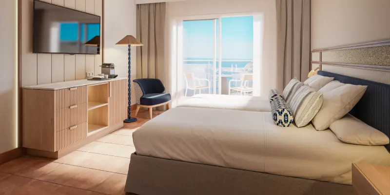 Habitaci&oacute;n de hotel moderna con cama, balc&oacute;n y zona de estar junto a ventana