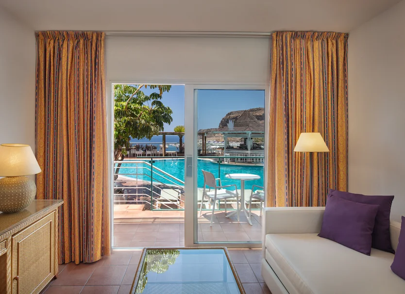 Vista desde el interior: terraza con piscina y mesa junto al mar