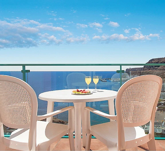 Mesa con dos copas y vista al mar desde una terraza junto al acantilado