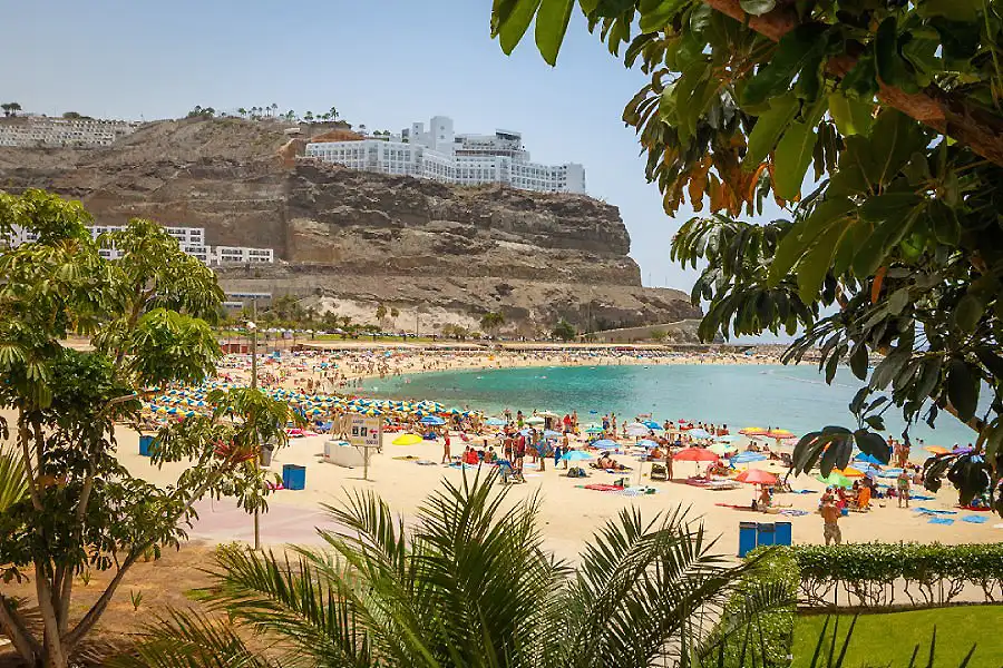 Playa tropical con hamacas y hotel al pie de un acantilado rocoso