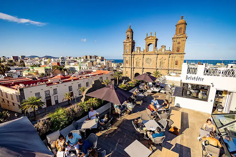 Plaza con terraza y catedral de estilo colonial frente al mar, en d&iacute;a soleado