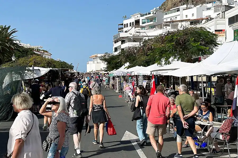 Gente paseando en un mercadillo al aire libre con puestos y carpas.