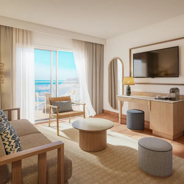 Habitaci&oacute;n de hotel moderna con cama, sill&oacute;n y balc&oacute;n al mar
