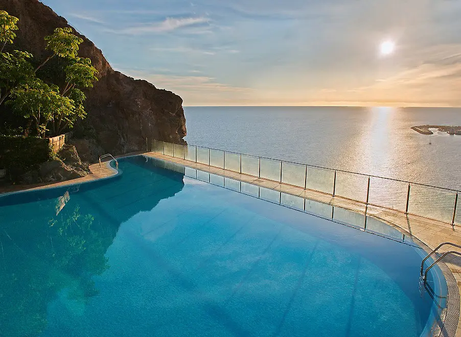 Piscina infinita con vista al mar y acantilado al atardecer