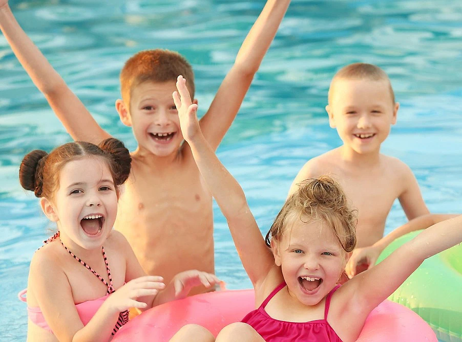 Ni&ntilde;os riendo en una piscina, jugando sobre flotadores de colores.