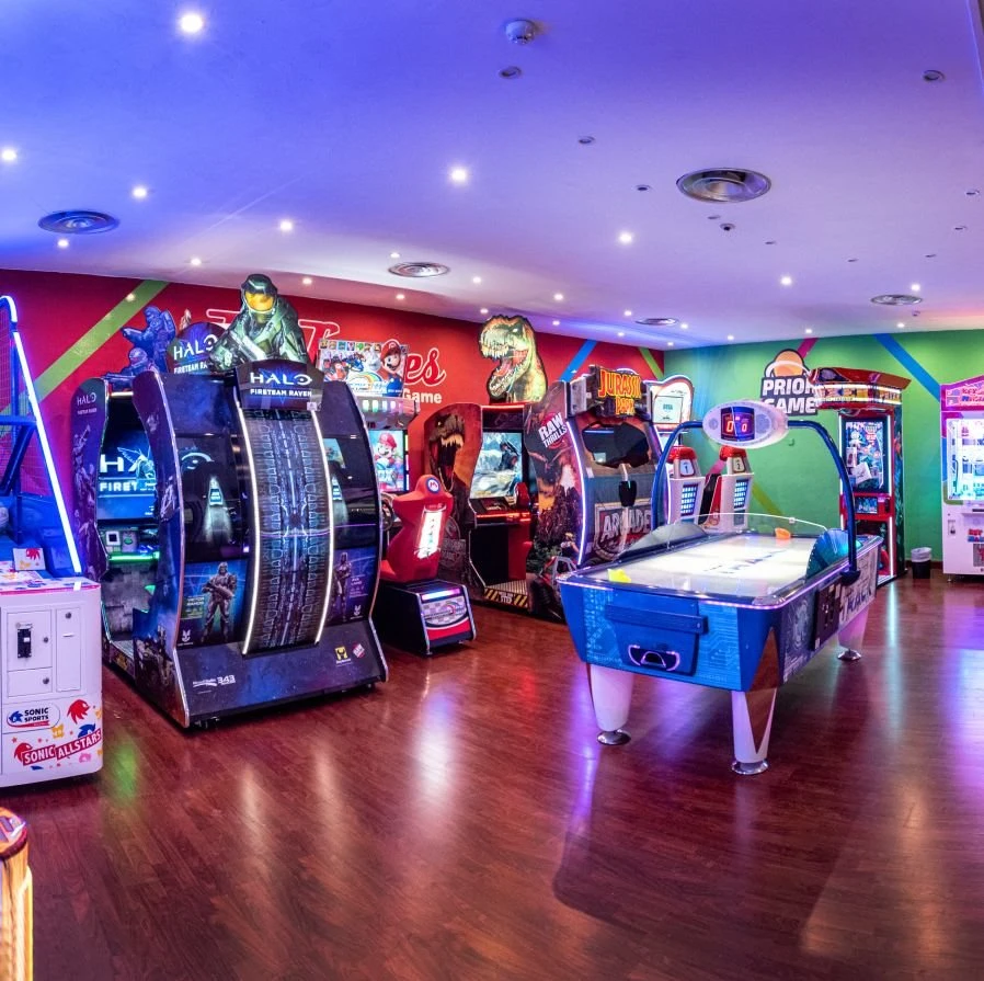 Sala de videojuegos infantil con m&aacute;quinas arcade y luces LED de colores