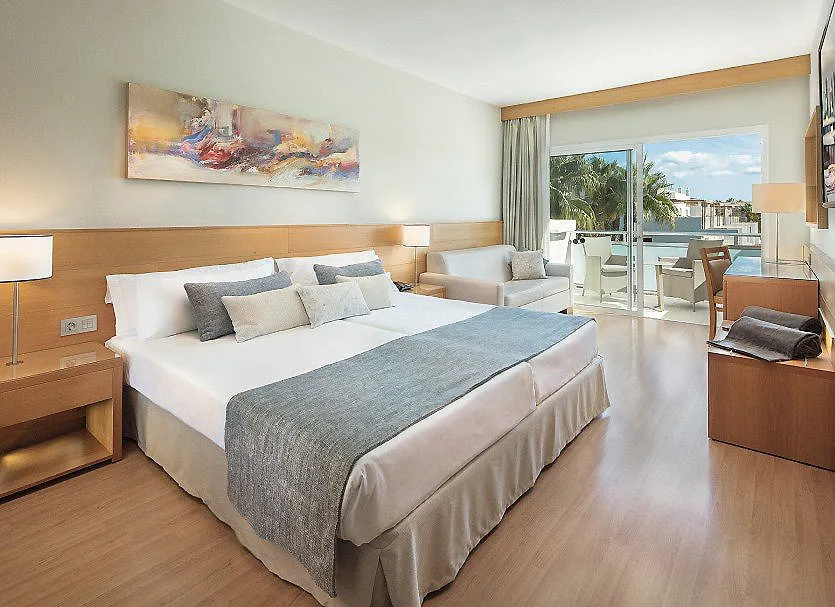 Habitaci&oacute;n de hotel con cama doble, sof&aacute; y balc&oacute;n con vista al mar