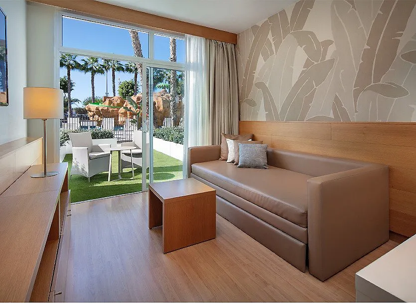 Sala moderna con sof&aacute; beige, mesa de madera y grandes ventanales al jard&iacute;n