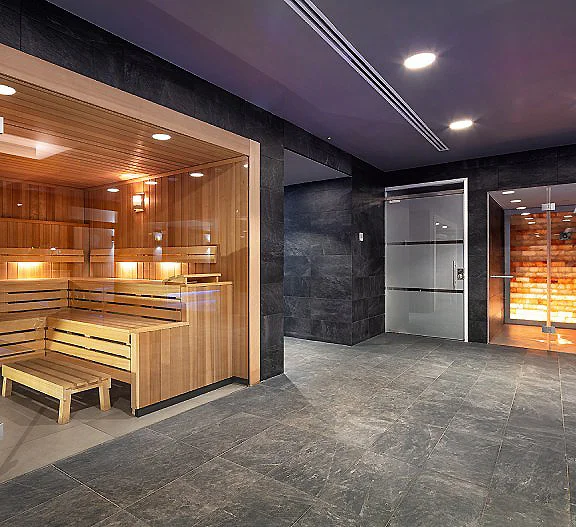Interior de spa con sauna de madera, ducha y piso de piedra gris