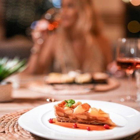 Plato gourmet con salsa roja y guarnici&oacute;n verde, en mesa de restaurante