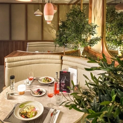 Cena rom&aacute;ntica en un restaurante con mesa puesta y plantas decorativas.